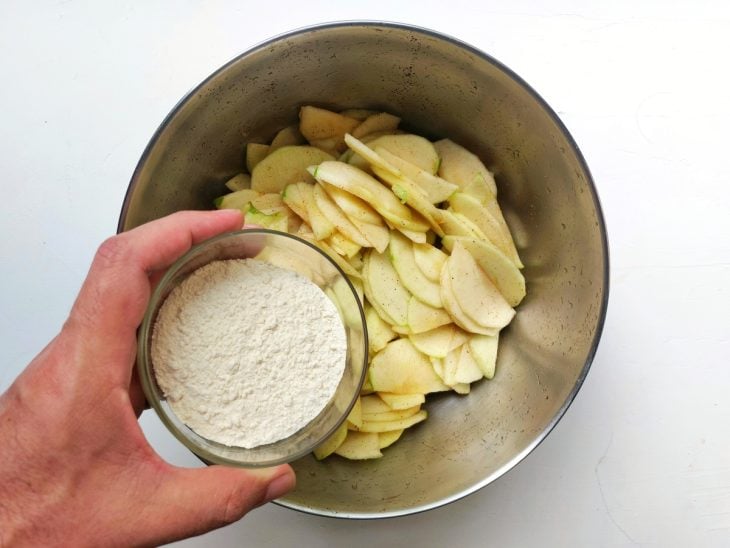Um recipiente contendo fatias de maçã com caldo de limão e farinha.