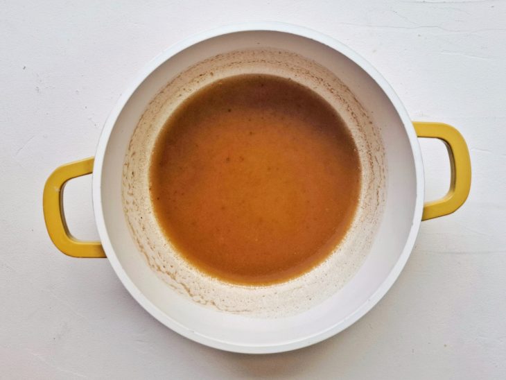 Uma panela com o caldo da maça e manteiga.
