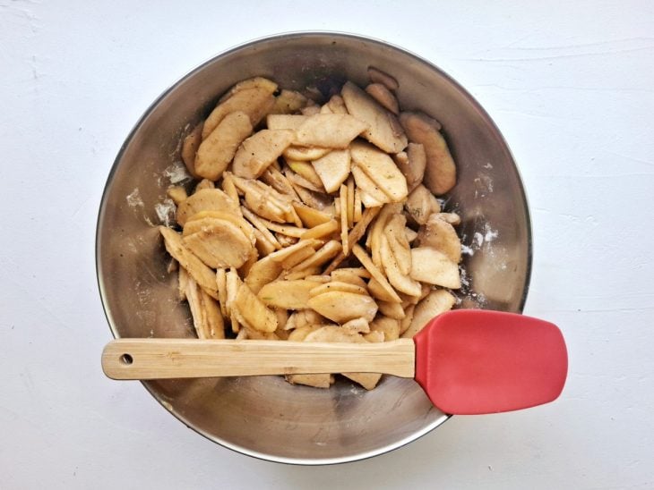 Uma bacia com as fatias de maçã e farinha.