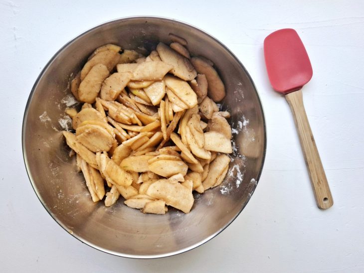 Uma bacia com as fatias de maçã, farinha e o caldo.