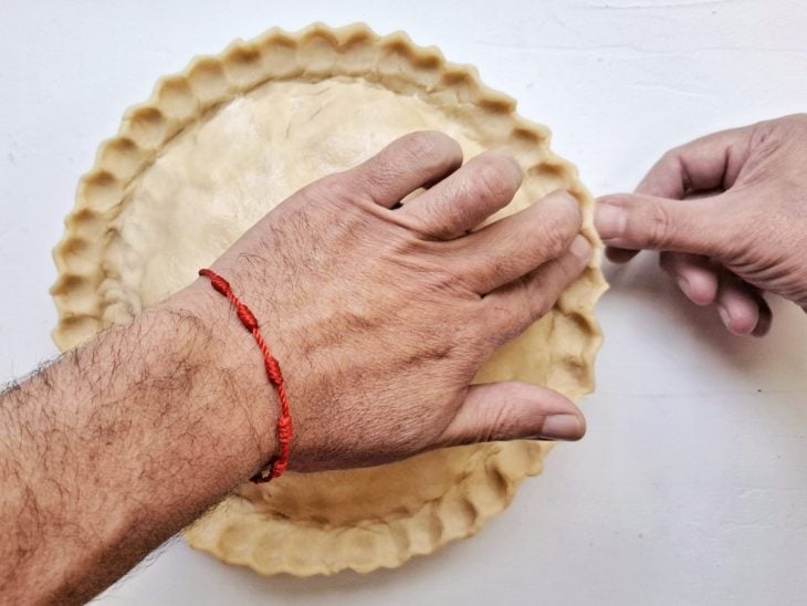 Uma forma com a torta de maçã e as bordas decoradas.