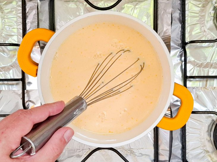 Creme sendo cozido na panela, mexido com fouet.