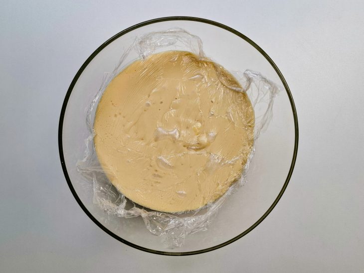 Creme espesso sendo transferido para um recipiente e coberto com plástico filme.