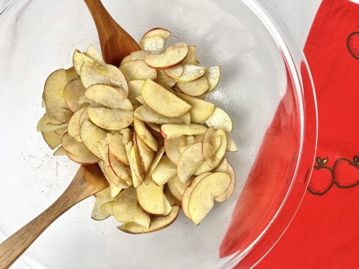 Uma tábua contendo maçãs fatiadas em meia-lua com açúcar e canela.