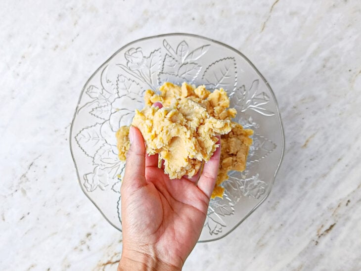 Ingredientes da massa sendo misturados com as pontas dos dedos até formar uma farofa.