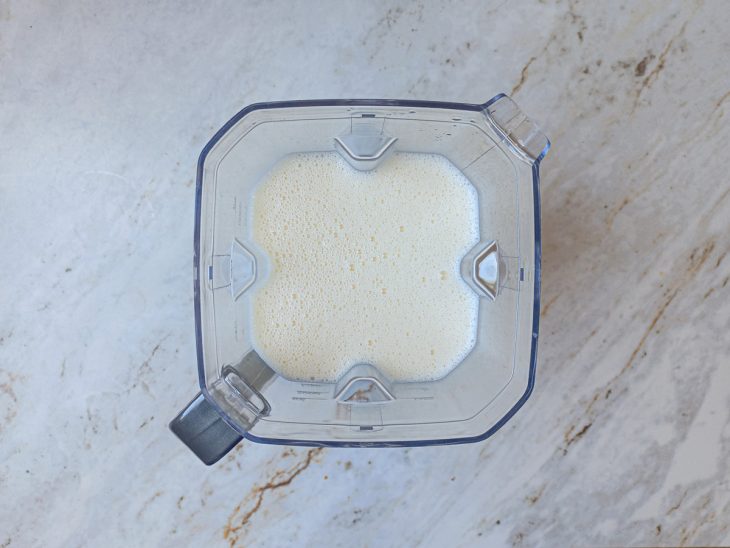 No liquidificador, a água quente, a gelatina sabor maracujá, o creme de leite, o leite condensado e o suco de maracujá batidos.