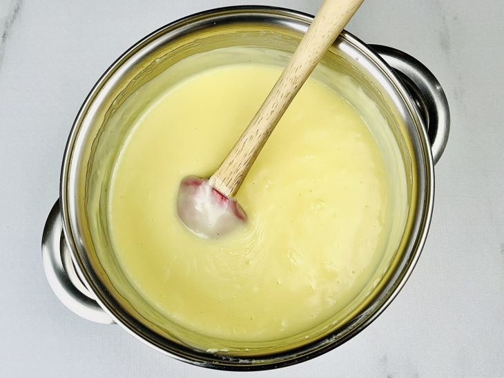 Leite condensado, creme de leite, essência de baunilha e gemas adicionados a panela.