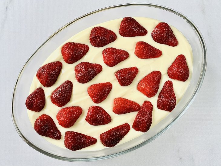 Morangos espalhados sobre o creme de banilha.