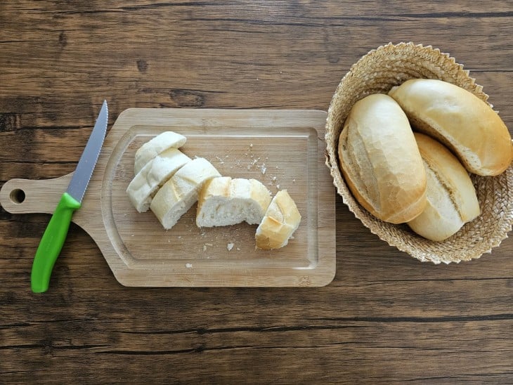 Pães do tipo francês sendo cortado em fatias.