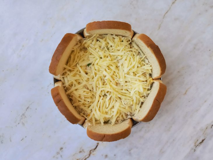 Recheio de frango e queijo mussarela adicionados em camadas a forma.
