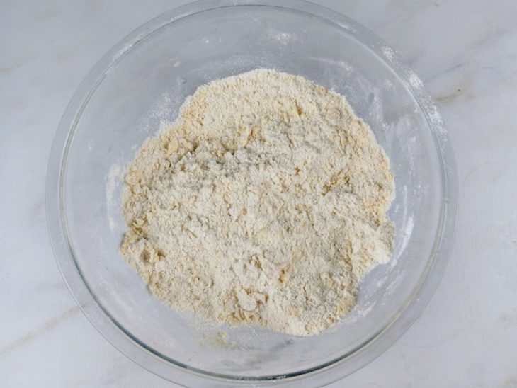 Farinha de trigo, açúcar, ovo, sal e fermento misturados em uma tigela de vidro.