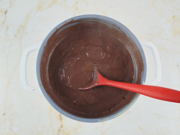 Creme de chocolate sendo mexido no fogo até engrossar levemente.