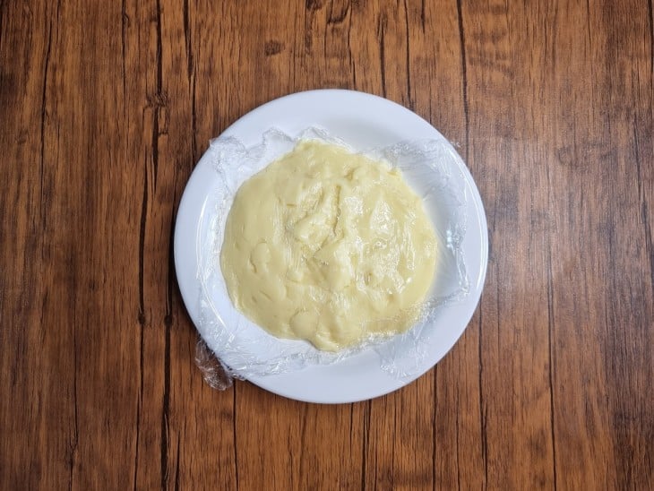 Creme branco colocado em um prato coberto por papel filme.