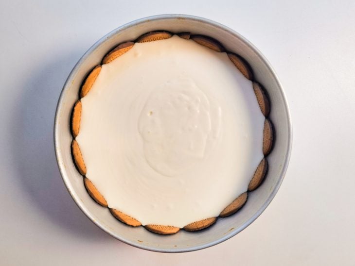 Creme despejado sobre a base de bolachas feita na forma.