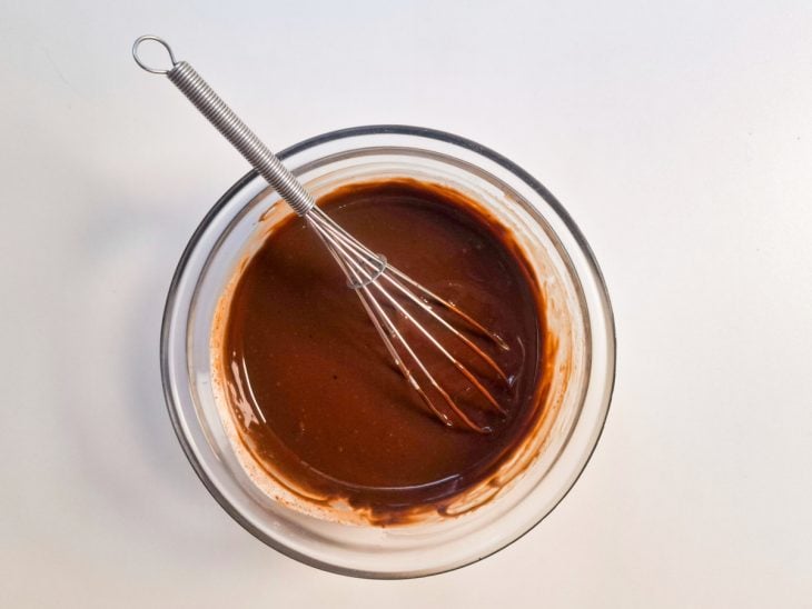 Ganache preparada em um recipiente redondo de vidro com auxílio de um fouet.
