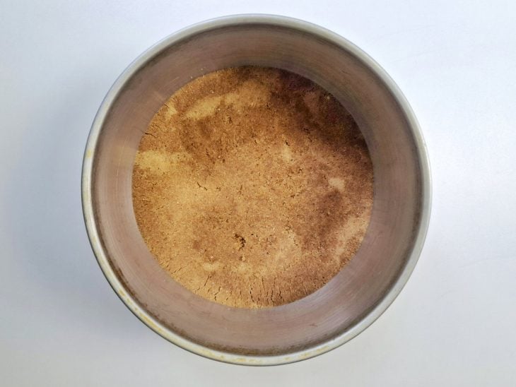 Base da torta feita com a bolacha maisena triturada ao forrando a forma.