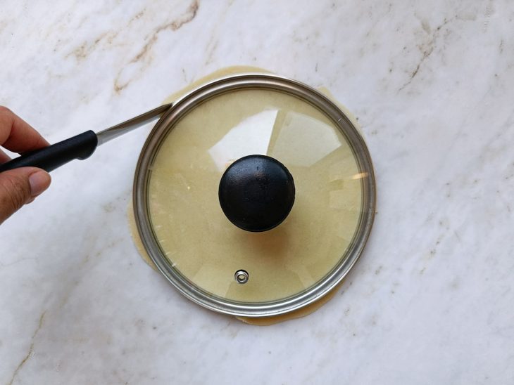 Massa sendo cortada com auxílio de uma tampa.