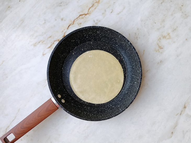 Massa da tortilha disposta na frigideira.