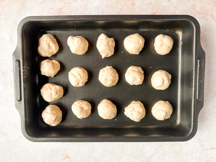 Bolinhas de massa descansando sobre assadeira.