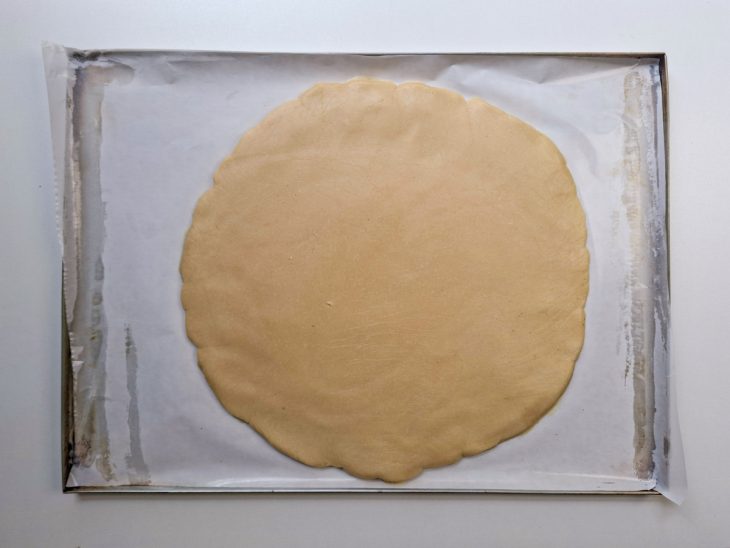 Massa sendo aberta sobre papel-manteiga.