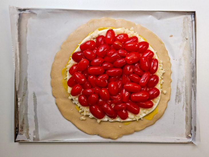 Tomatinhos organizados sobre os queijos de forma decorativa.