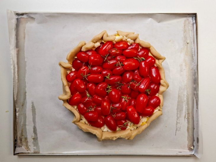 Raminhos de tomilho distribuídos sobre os tomates e bordas pinceladas com ovo.