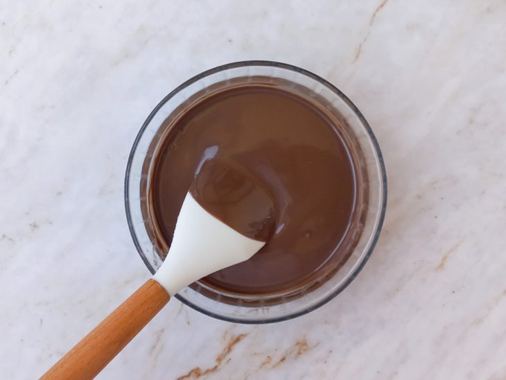 Chocolate derretido num recipiente redondo de vidro.