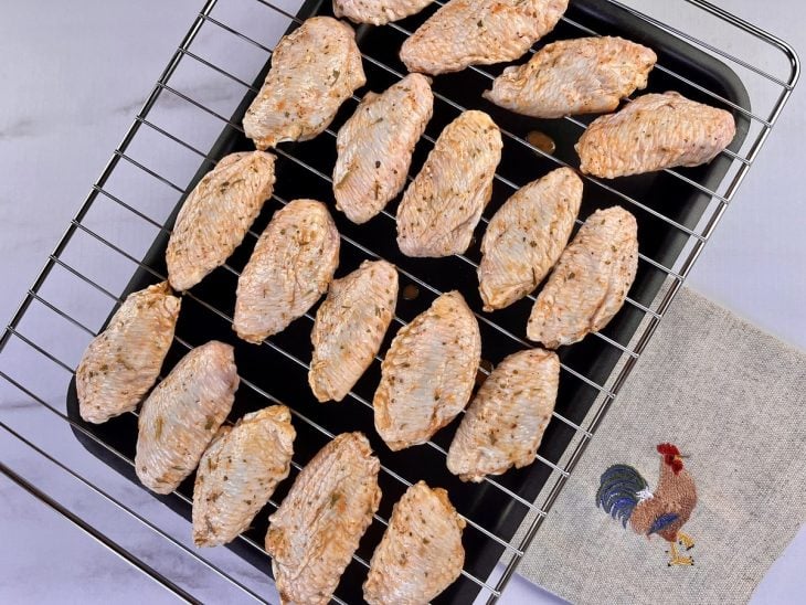 Tulipas de frango dispostas organizadamente em cima de uma grade de forno.