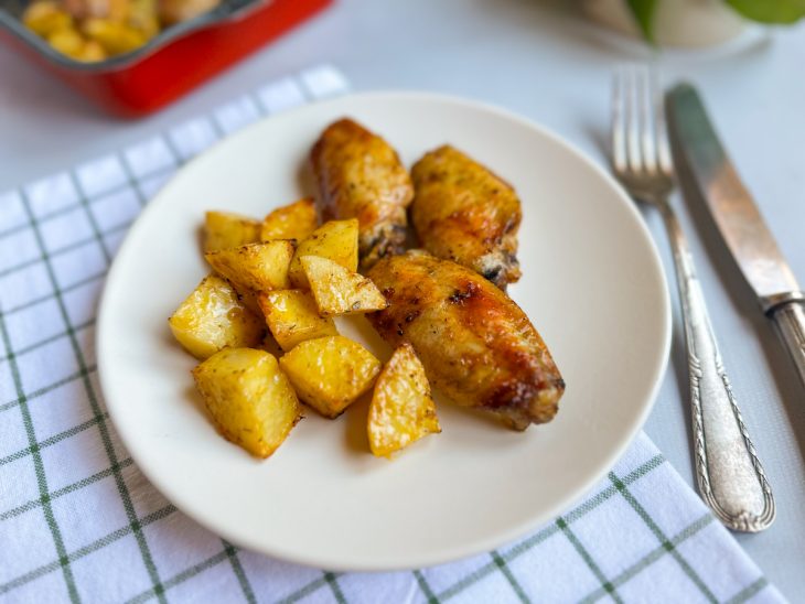 Tulipas e batatas prontas, servidas em prato, talheres ao lado completam o quadro.