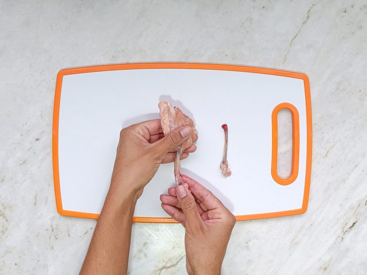 Frango sendo cortado e modelado no formato.