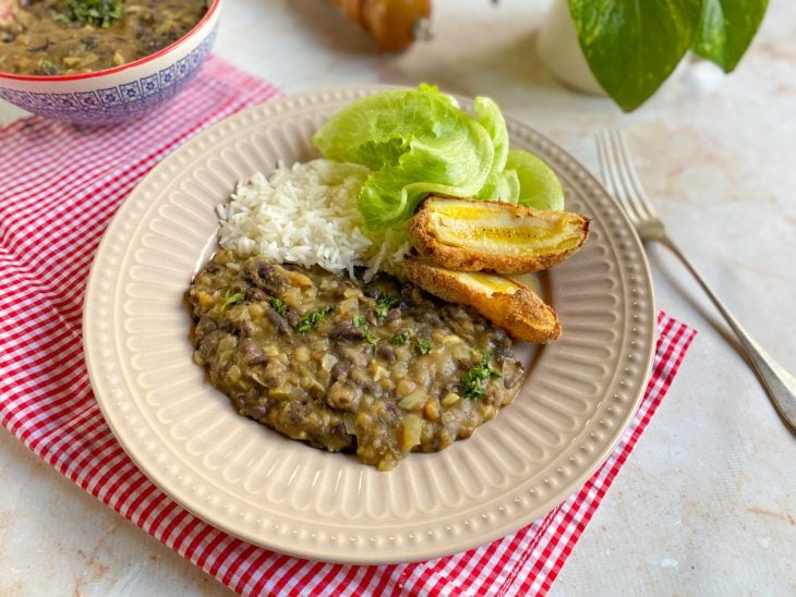 Tutu de feijão simples servido com arroz, alface e banana frita em um prato.