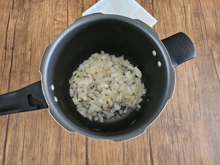 Panela de pressão com cebola refogando.