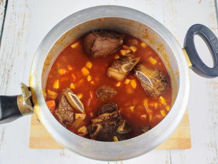 Água fervente e tomates picados adicionados na panela de pressão.