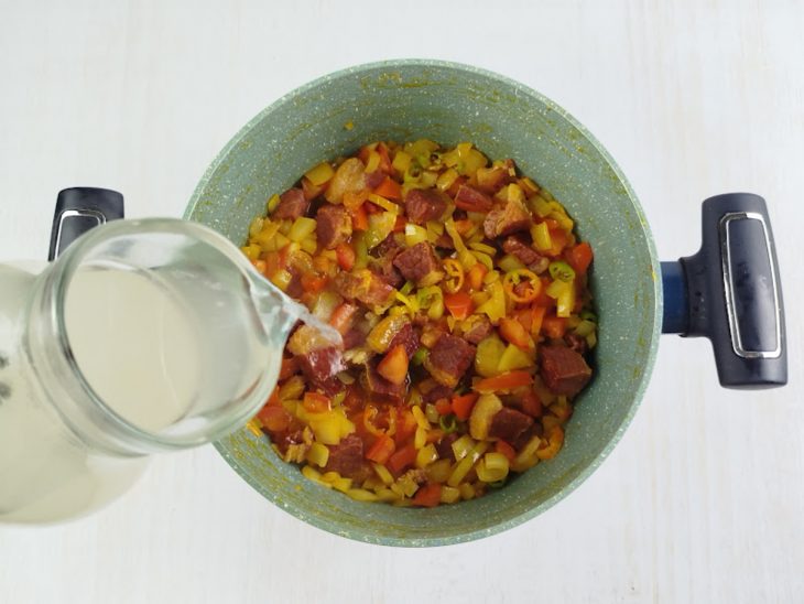 Caldo do charque adicionado à panela.