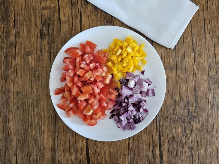 Prato com tomate, cebola e pimentão cortados em cubos.