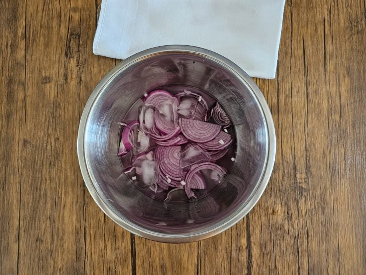 Água, gelo e cebola roxa em uma tigela.