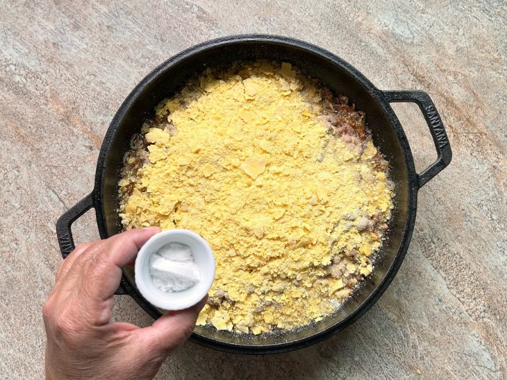 Feijão, farinha e sal adicionados a panela com alho e cebola.