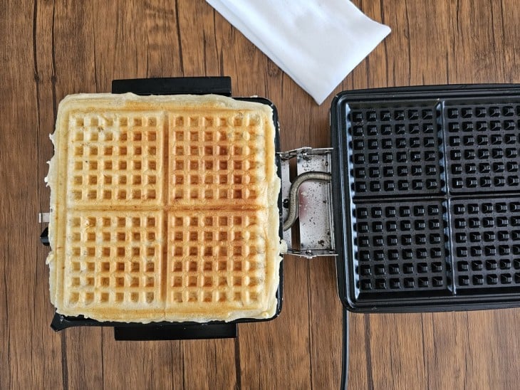 Uma máquina de waffle contendo waffles de pão de queijo.