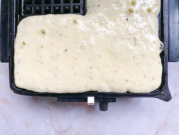 Massa de waffle sobre a chapa da máquina de waffle.