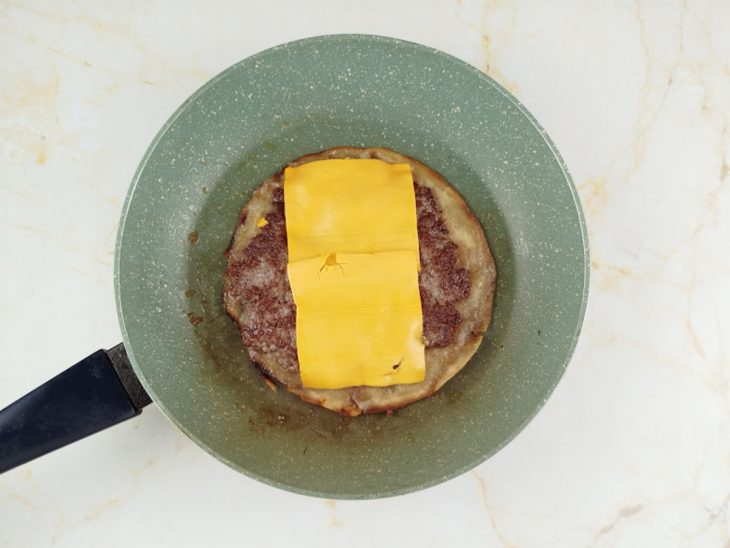 Queijo adicionado por cima da carne.