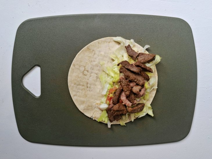 Wrap sendo recheado com a guacamole e a carne.