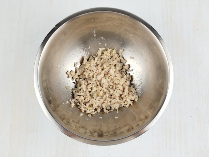 Frango desfiado e temperado em uma tigela.