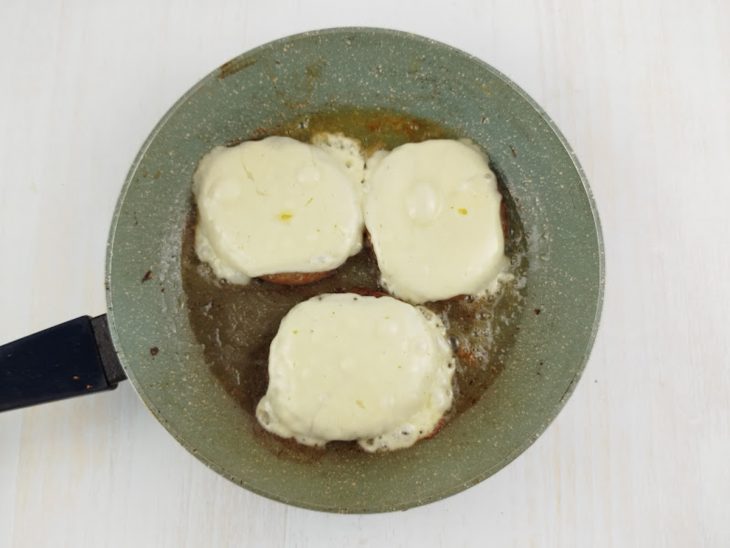 Queijo derretido sobre os hambúrgueres na frigideira.