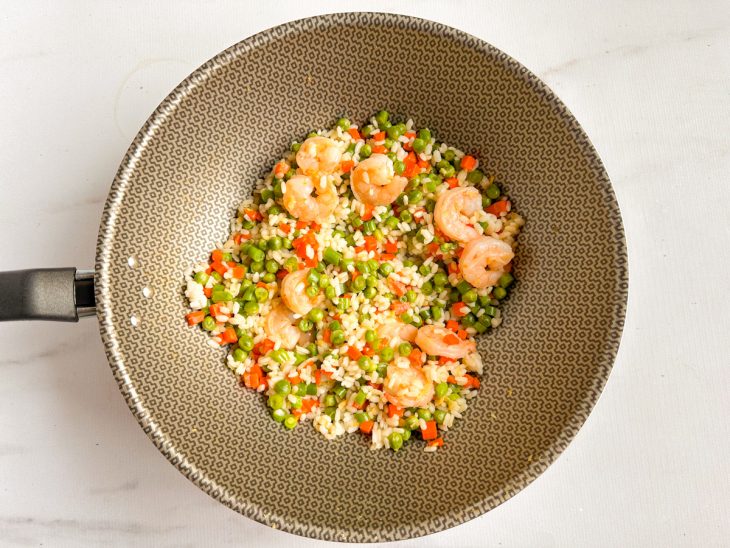Arroz adicionado à mistura de camarão e legumes.