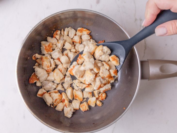 Frango fritando em uma frigideira com azeite.