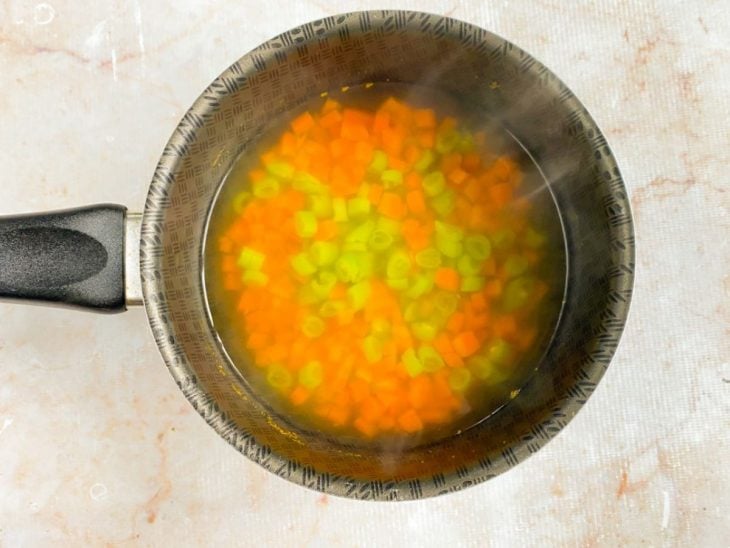 Cenoura e vagem em uma panela com água fervente.
