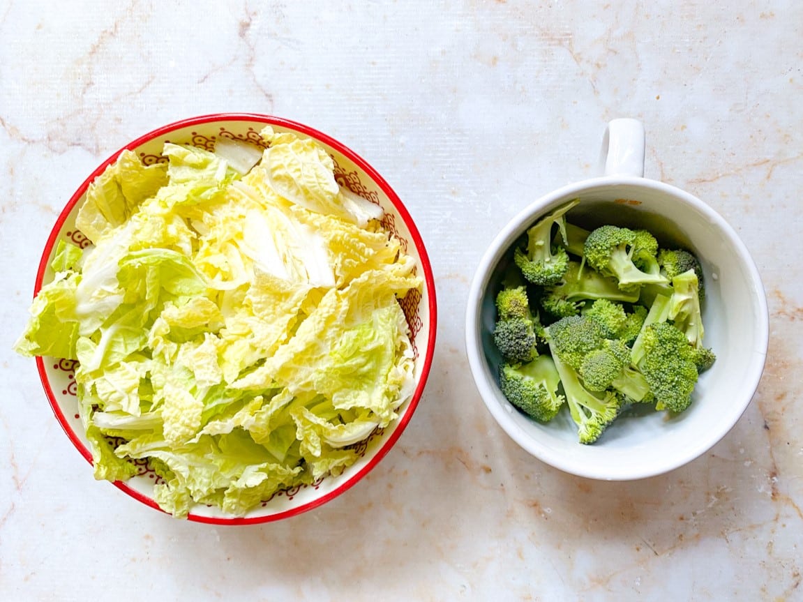 Acelga e brócolis higienizados e picados em recipientes separados.